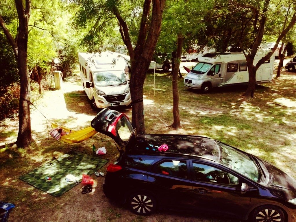 Kemping w Maslinie samochody, kamery i dziewczyna leżąca w hamaku, Czarnogóra.