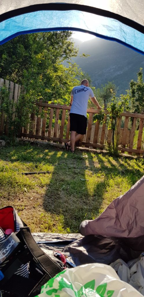 Mężczyzna widziany z namiotu opierający się o płot.