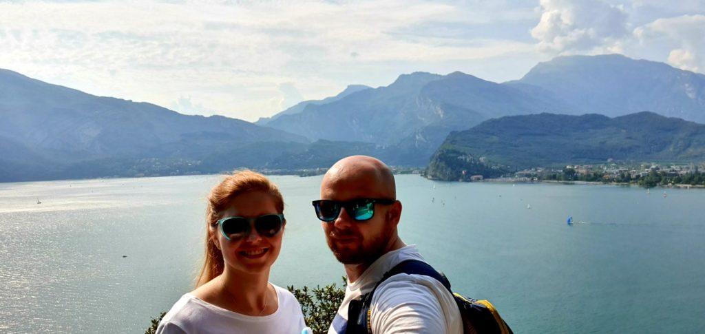 Para w ciemnych okularach nad jeziorem Garda w słoneczny dzień.