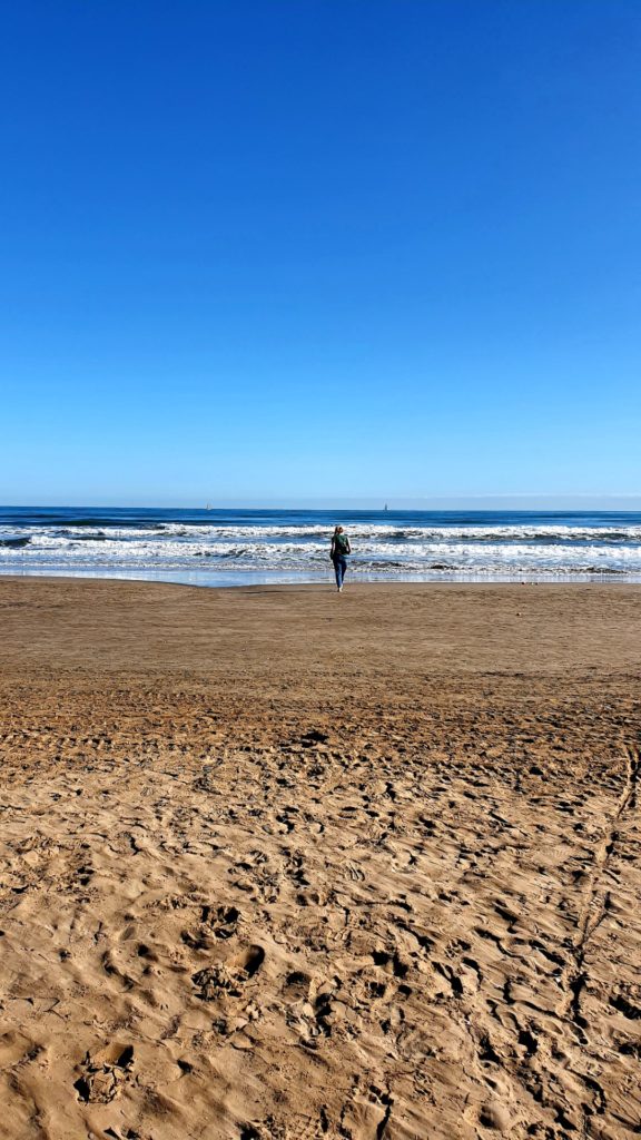 Dziewczyna spacerująca po plazy w Walencji w piękny, słoneczny dzień.