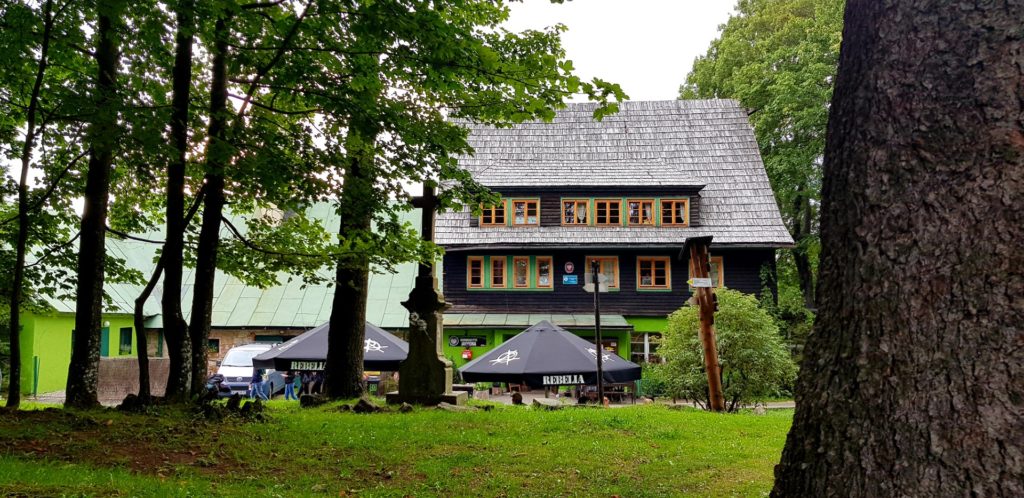 Budynek schroniska widziany spośród drzew.