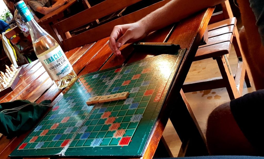 Człowiek grający w Scrabble przy winie.