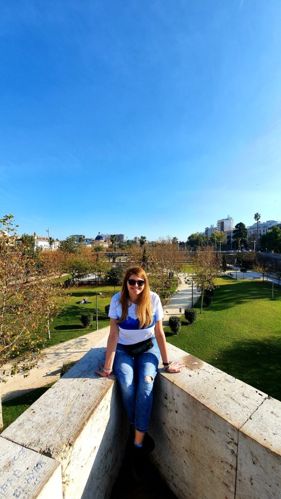 Dziewczyna w okularach słonecznych siedząca na murku nad Turią w Walencji w piekny słoneczny dzień.