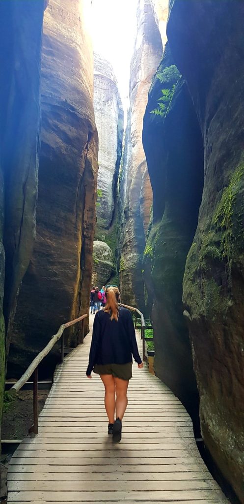 Dzewczyna przechadzająca się drewnianą ścieżką wśród skał. Skalne miasto w Górach stołowych