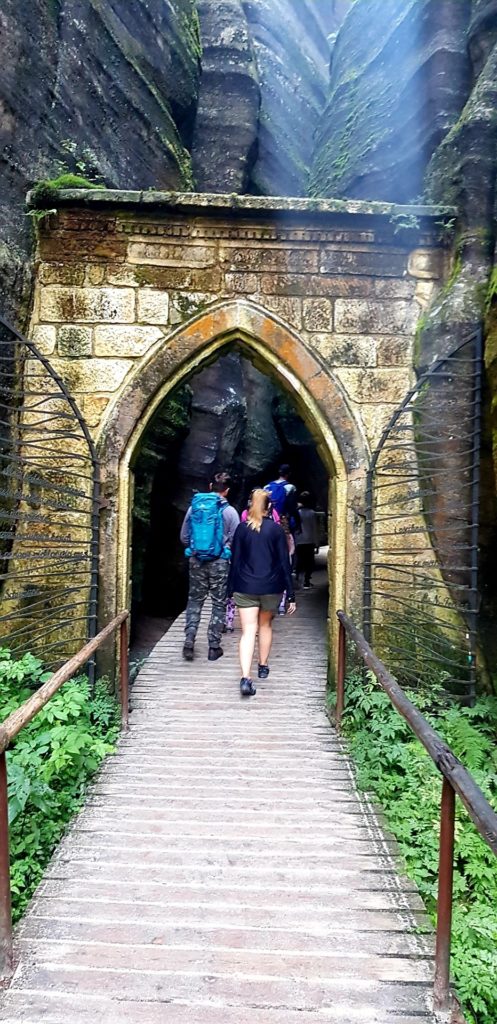 Dziewczyna przechodząca przez skalną bramę w Adrspach, Góry stołowe.