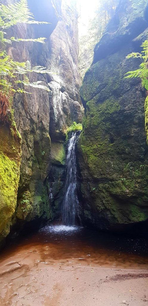Wodospad wpadający do małego jeziorka wśród skał. Góry Stołowe.