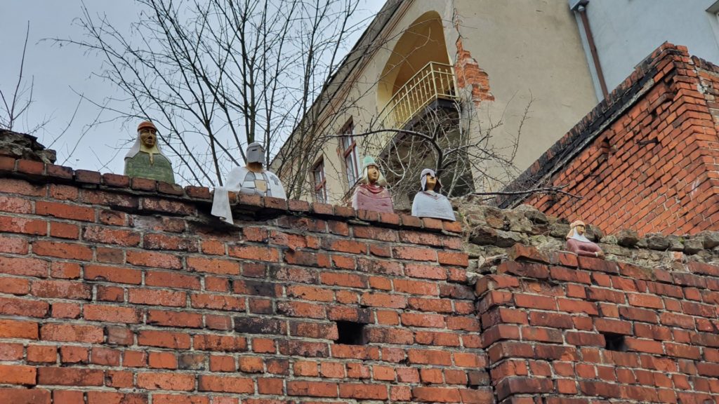 Figurki spoglądające z muru na starówce w Toruniu