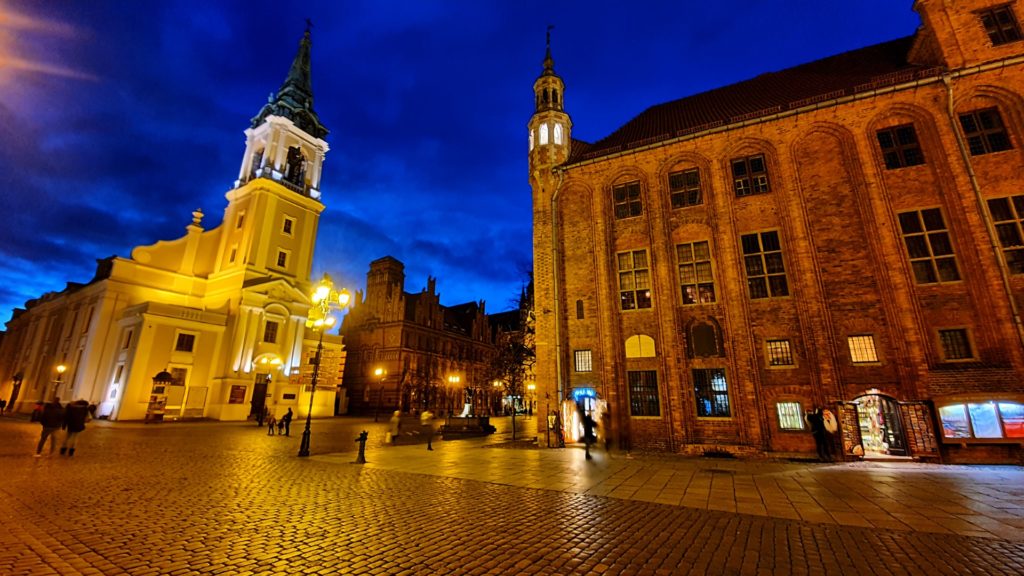 Widok starówki w Toruniu nocą ładnie oświetlony ratusz