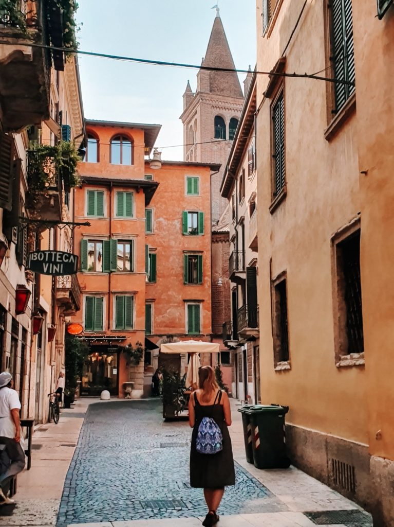 Dziewczyna z plecakiem wsukience przechadza się ulica Werony.