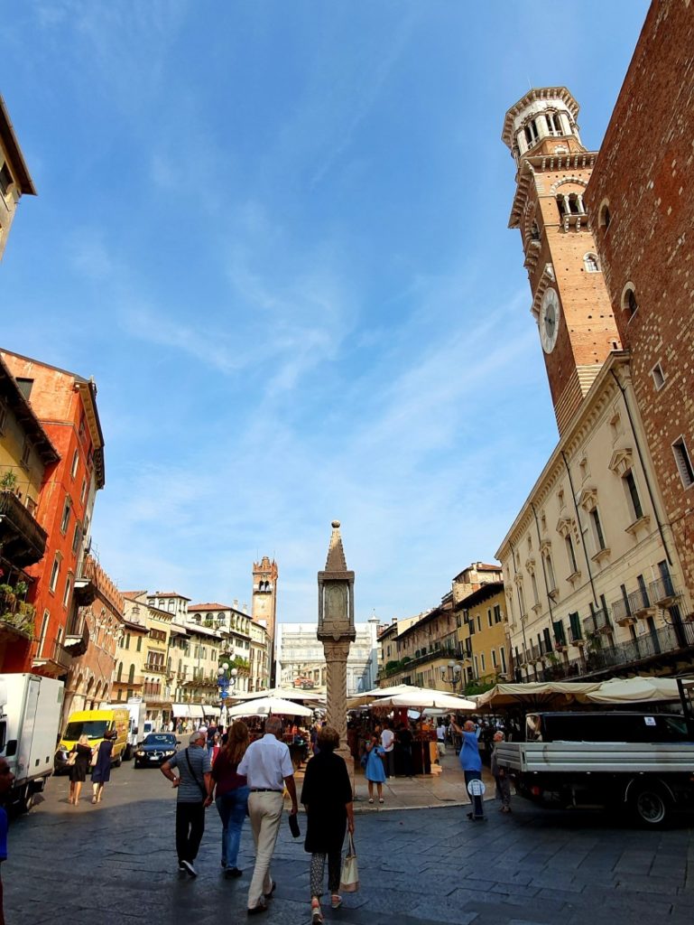 Nasłoneczniony plac w Weronie otoczony zabytkowymi kamienicami,
