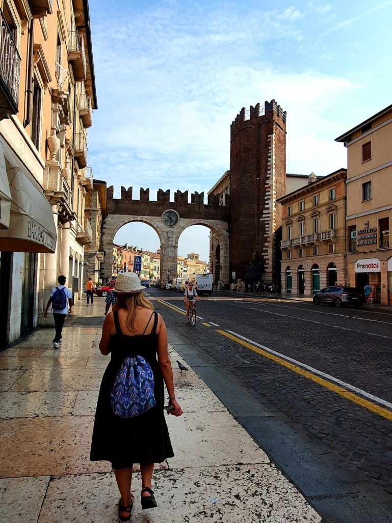 Dziewczyna w kapeluszu i sukience przechadza się ulica Werony.