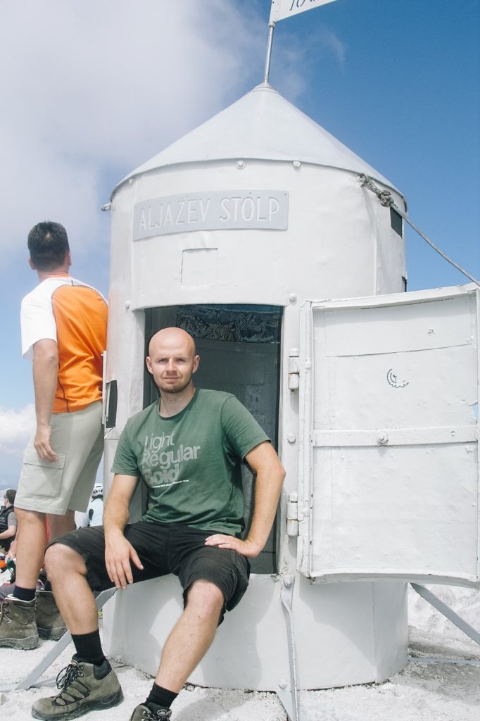 Mężczyzna siedzący na wierzchołku Triglava, schron na szczycie.