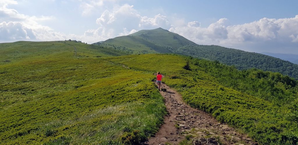 Samotna dziewczyna na bieszczadzkim szlaku. Zielone szczyty gór.