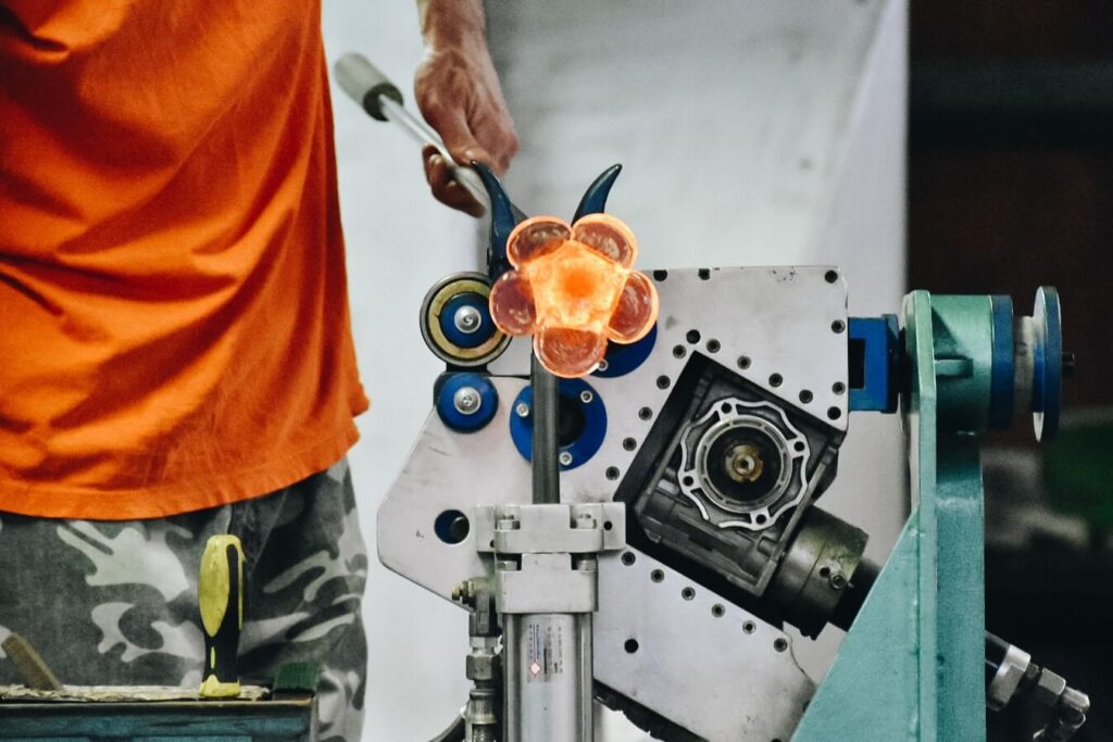 Pracownik huty wyrabiający szklane produkty.