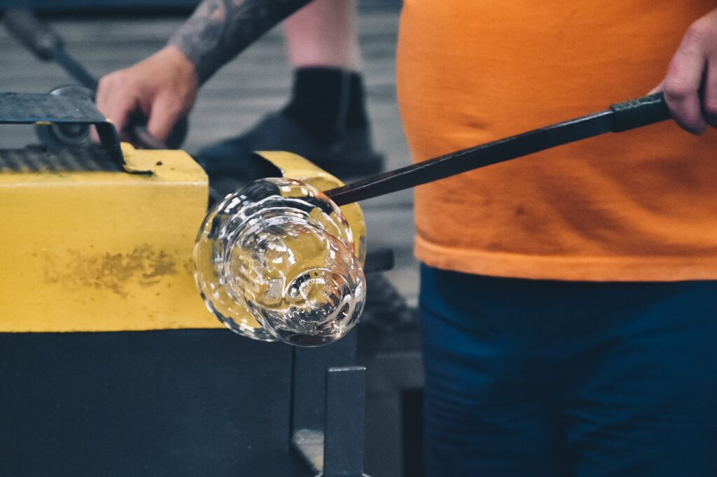 Pracownik huty wyrabiający szklane produkty.