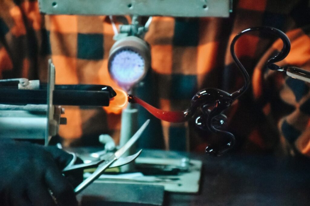 Pracownik huty wyrabiający szklane rzeźby.