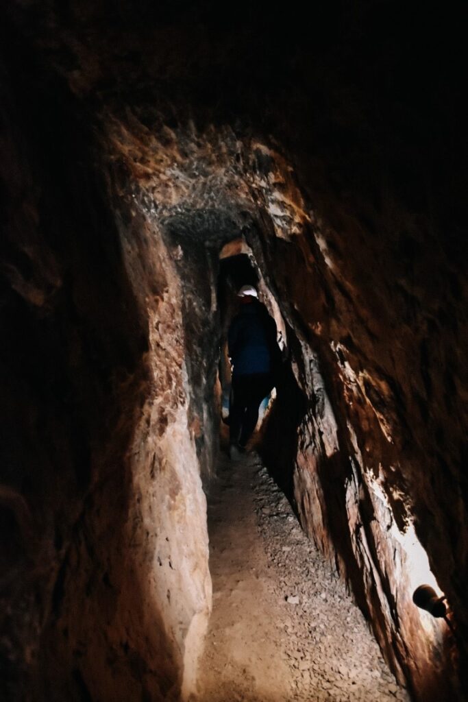 Dziewczyna przeciskająca się przez wąski tunel kopalni.