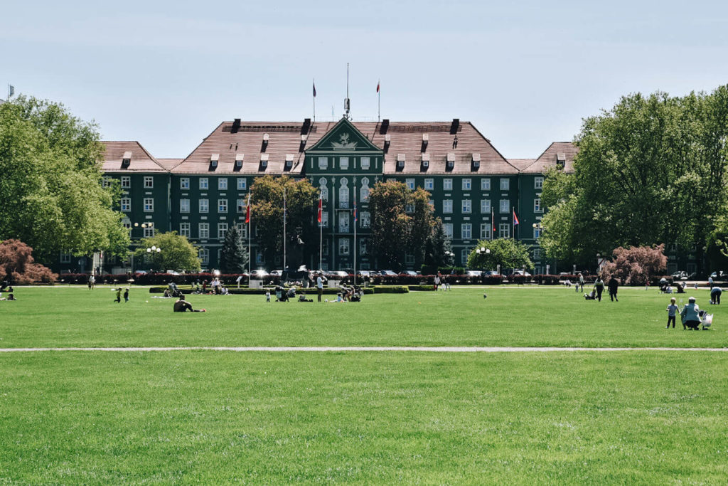 Ludzie wypoczywający na trawniku przez Urzędem Miasta w Szczecinie. Plac Jasne Błonia.
