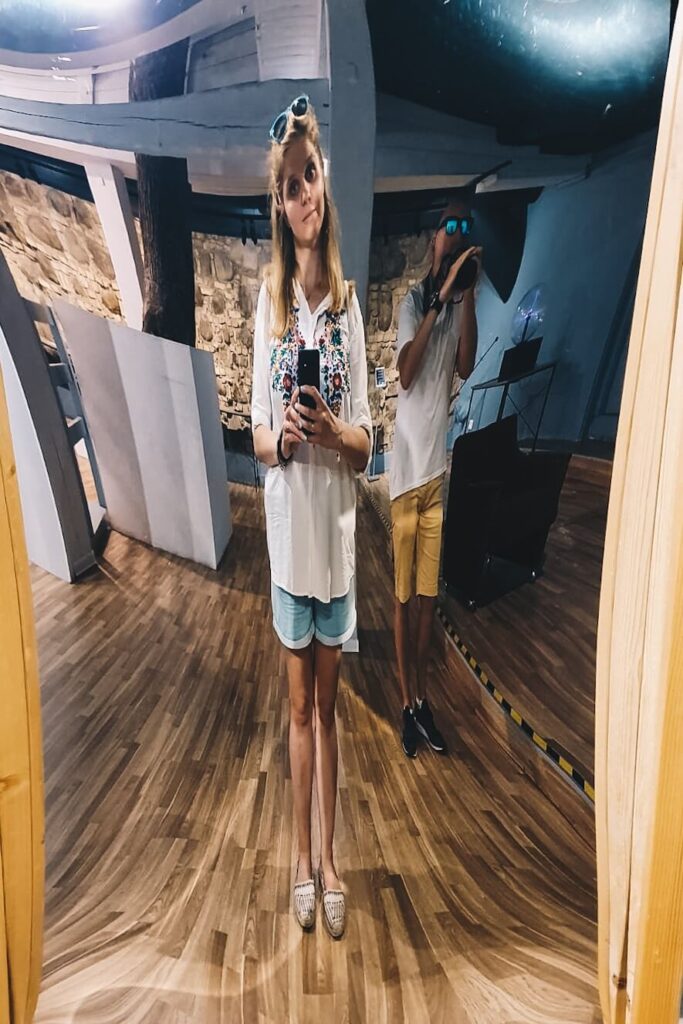 Odbicie dziewczyny w krzywym zwierciadle w Muzeum Iluzji w Wilnie.