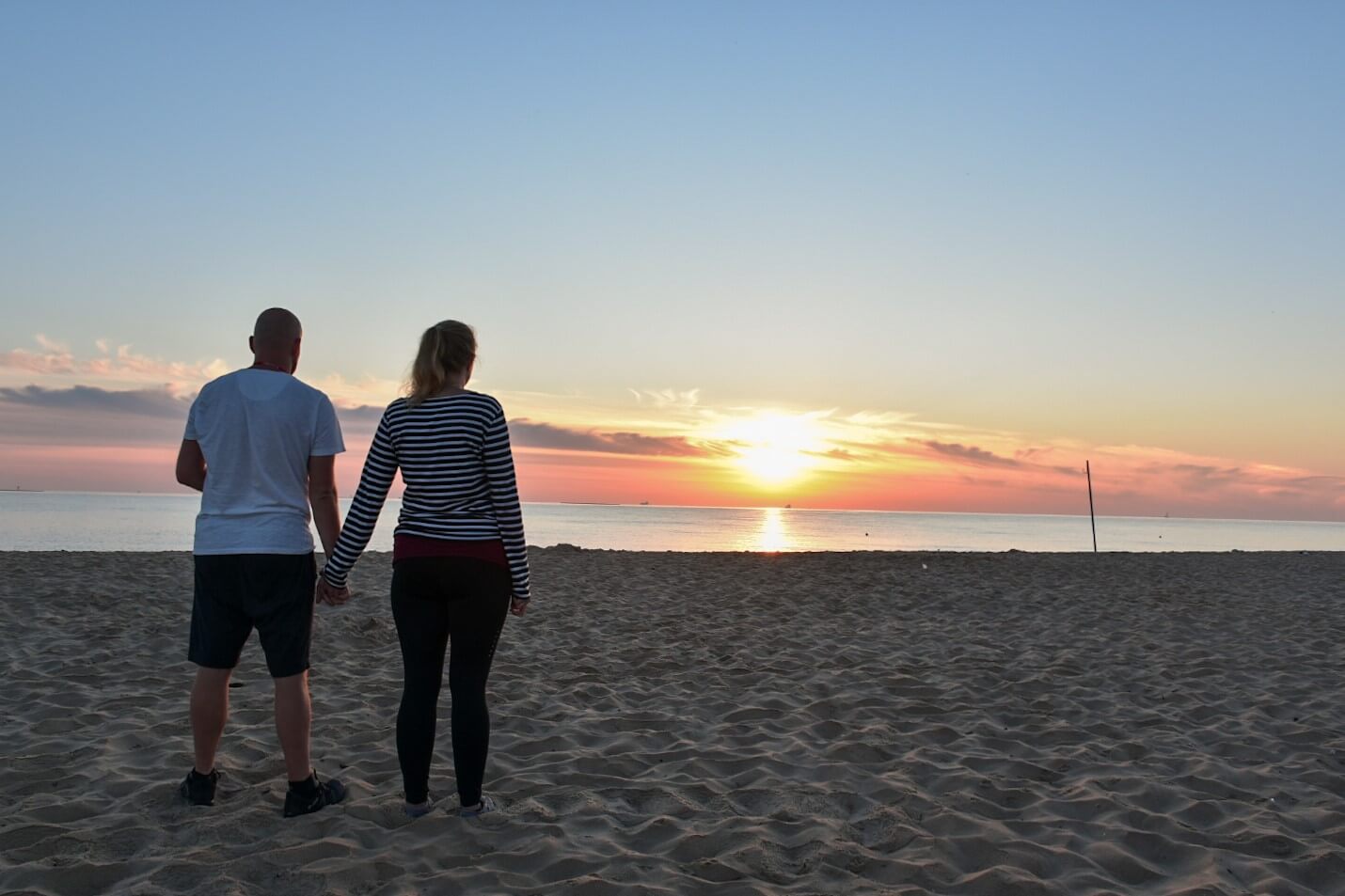 Prara trzymająca się za ręce na plaży o wschodzi Słońca.