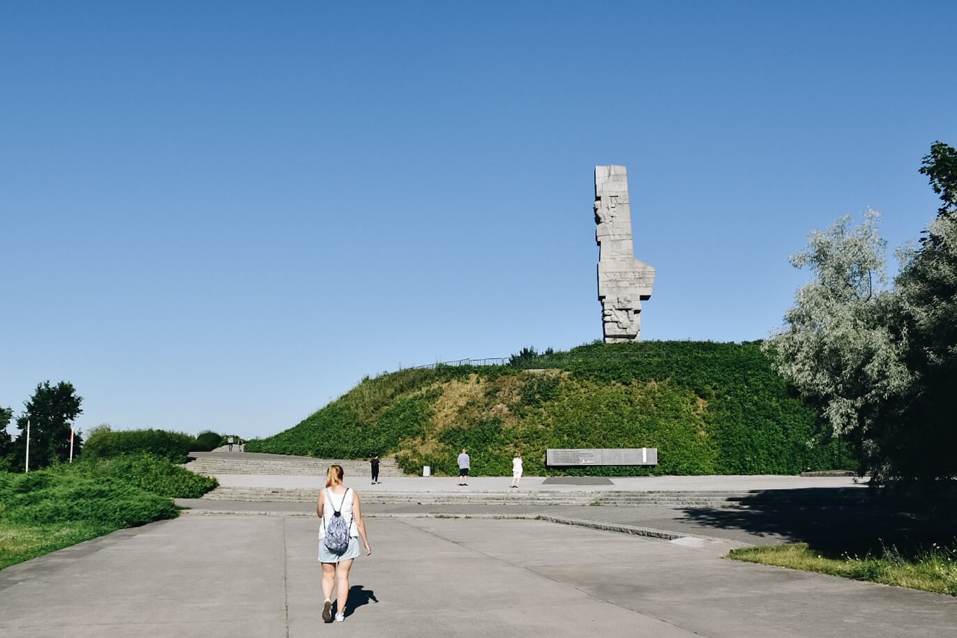 Turystka spacerująca po Westerplatte w tle Pomnik Obrońców Wybrzeża.