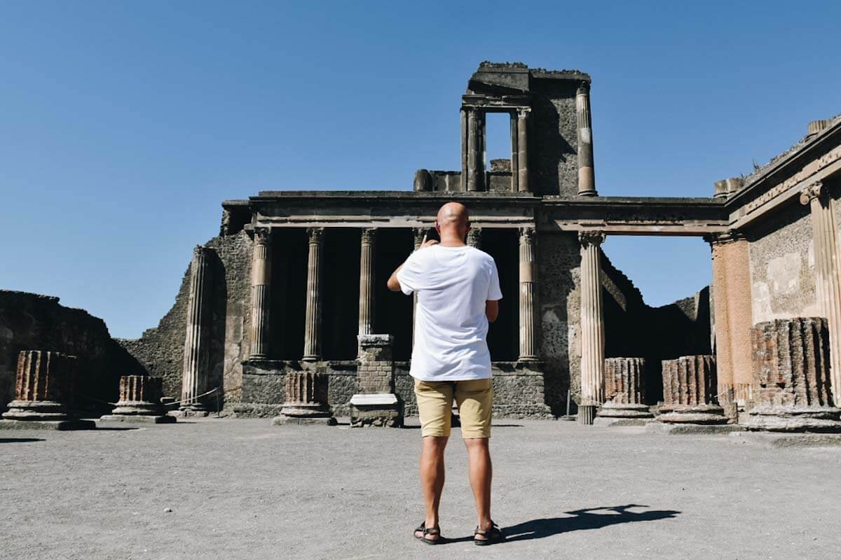 Turysta przyglądający się ruinom we włoskich Pompejach.