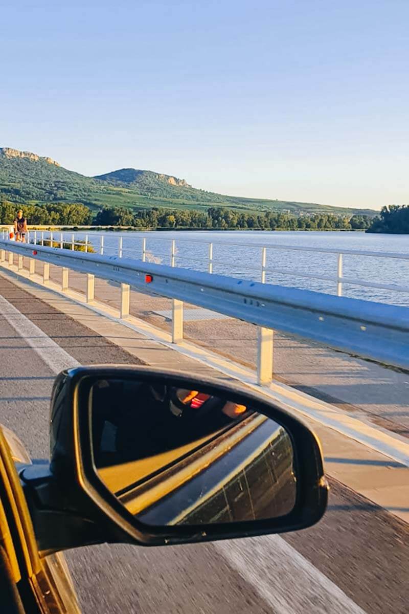 Widok z samochodu na trasę i otaczające jezioro.